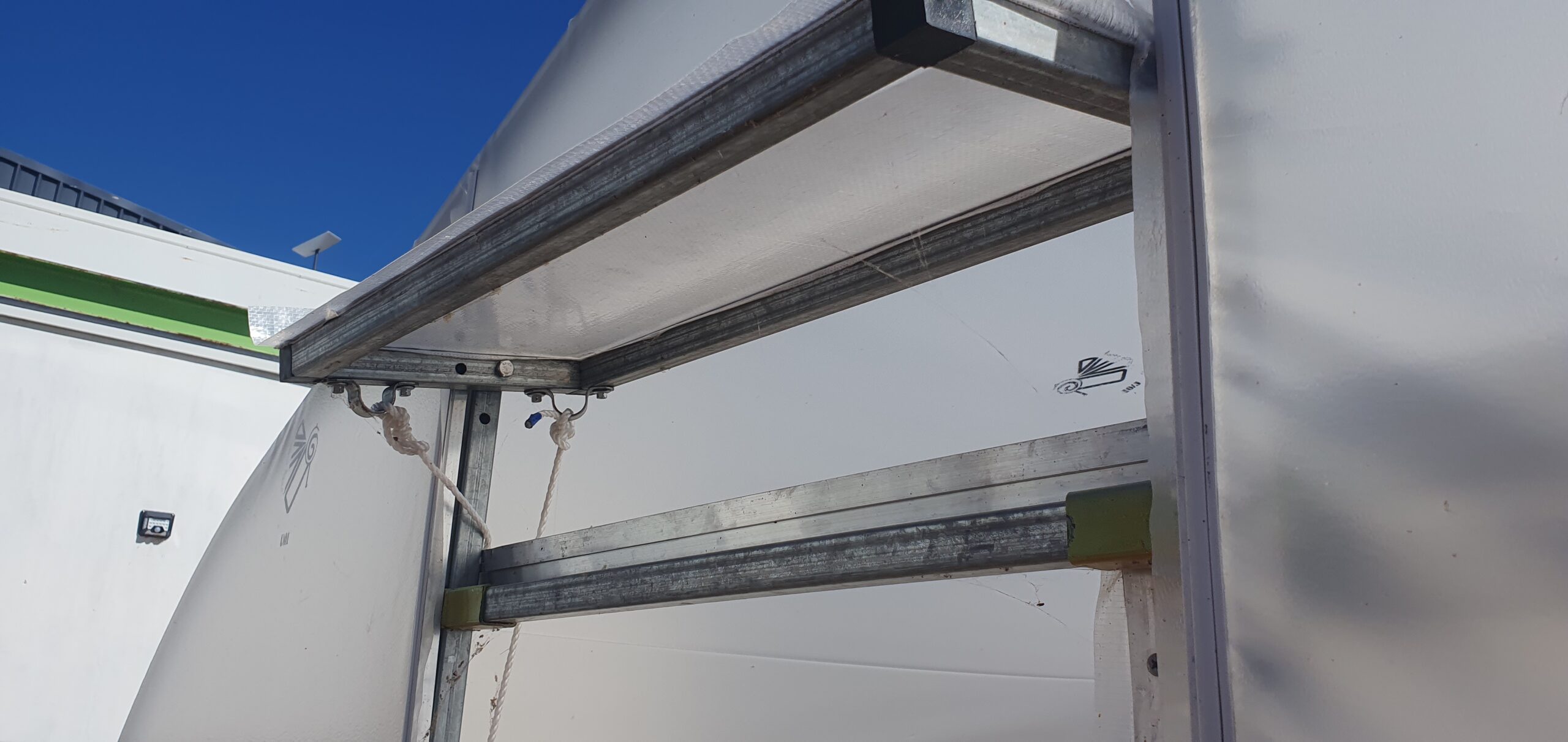 Closeup view of window ventilation system for domestic greenhouse