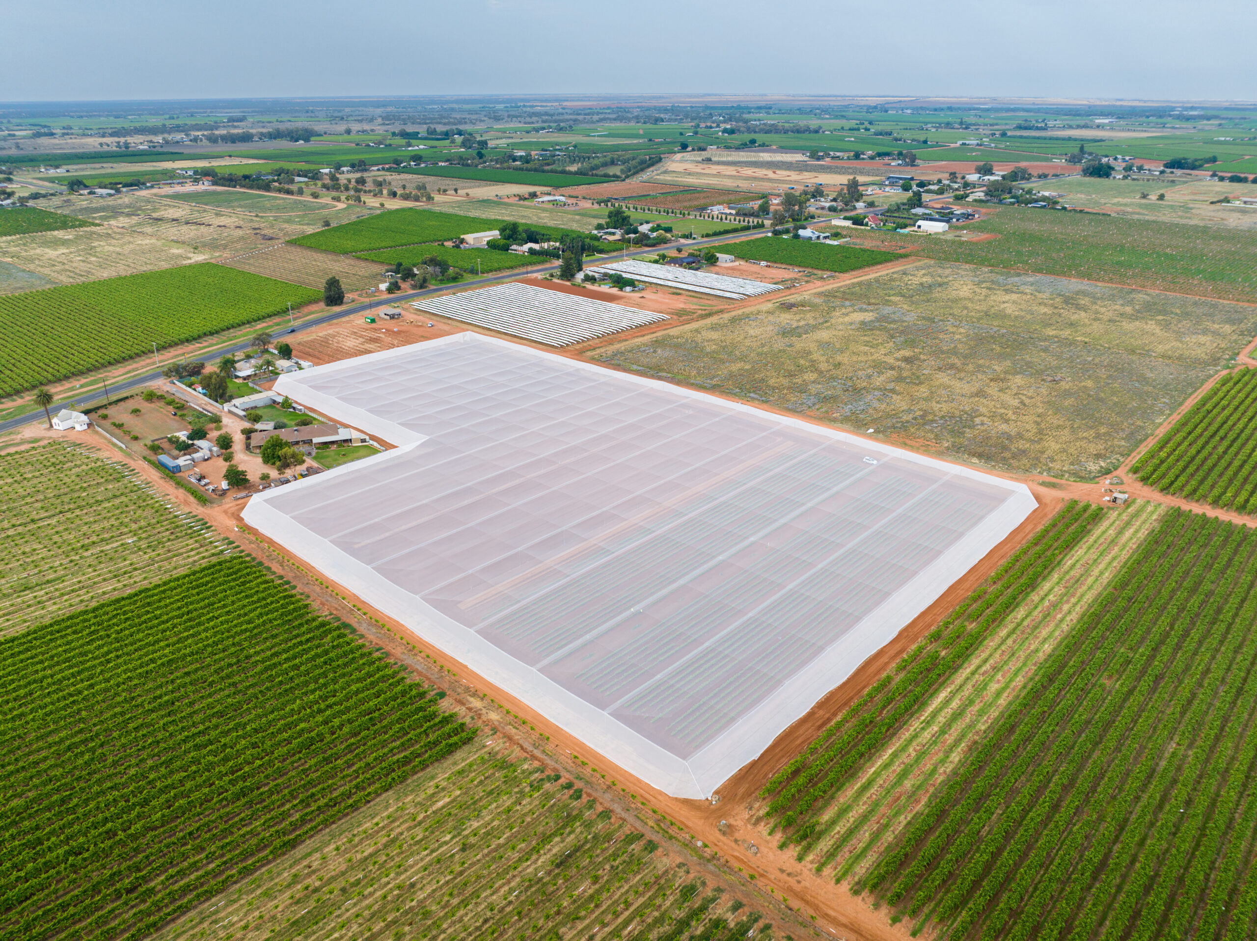Drone shot - birds eye view - large fields with large netting installation in center